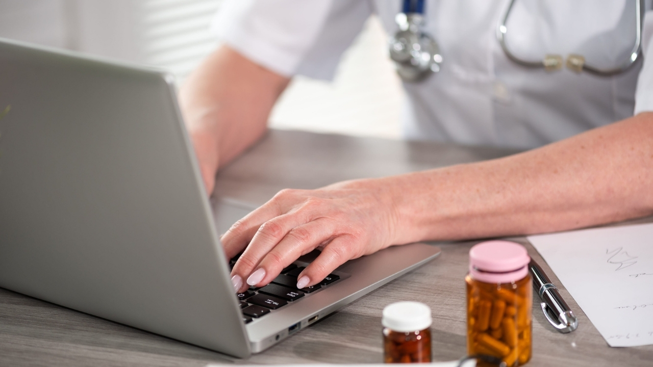 Doctor uses a laptop beside prescription bottles for a telehealth consultation