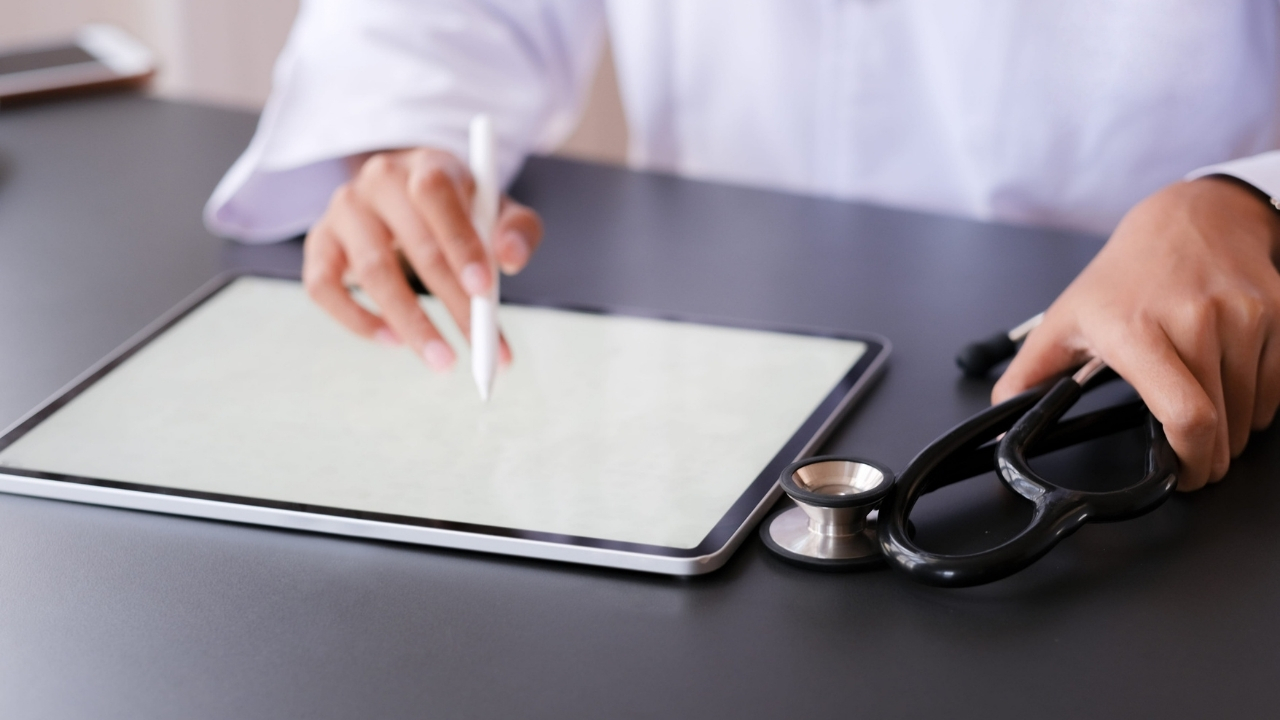 Doctor reviews a tablet beside a stethoscope