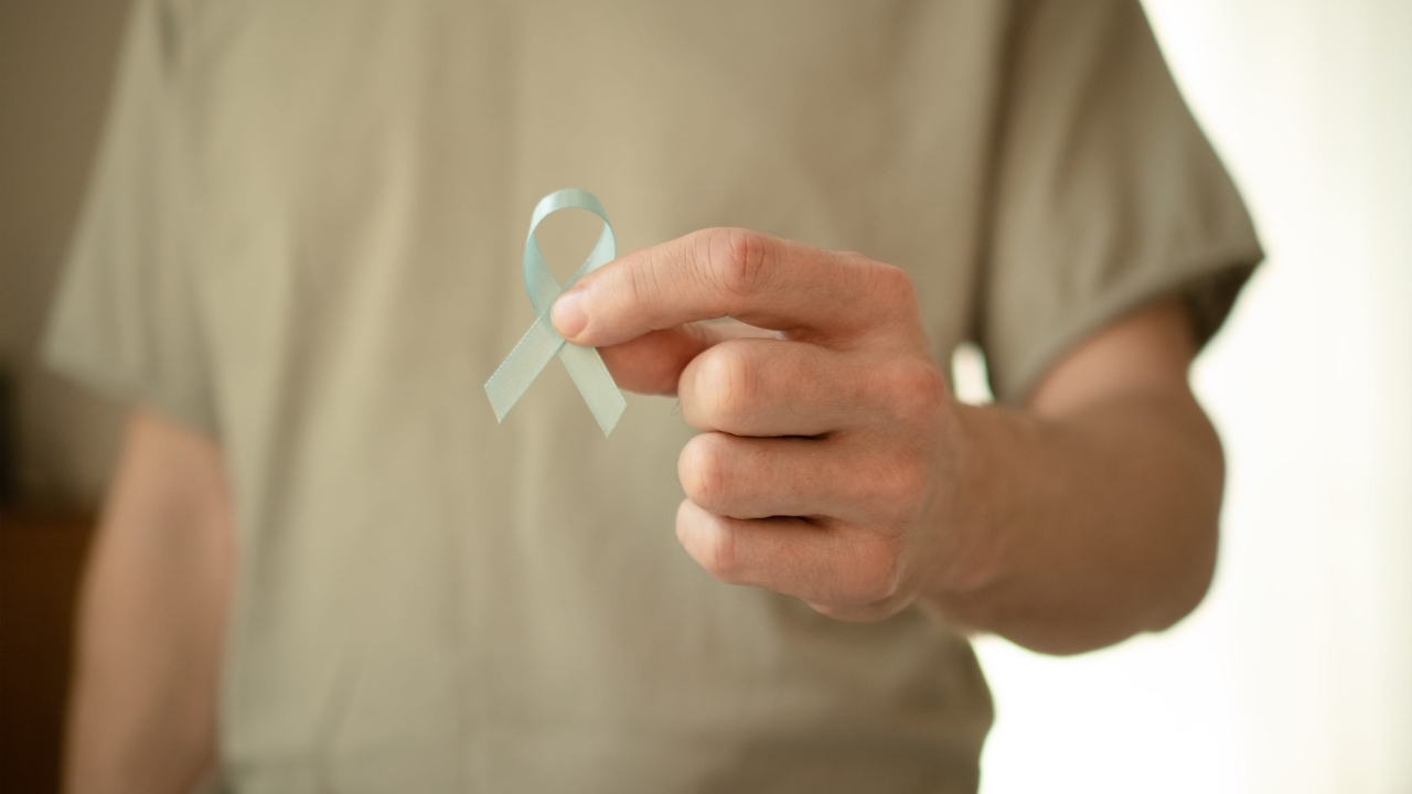 A man holds a light blue ribbon for prostate cancer awareness.