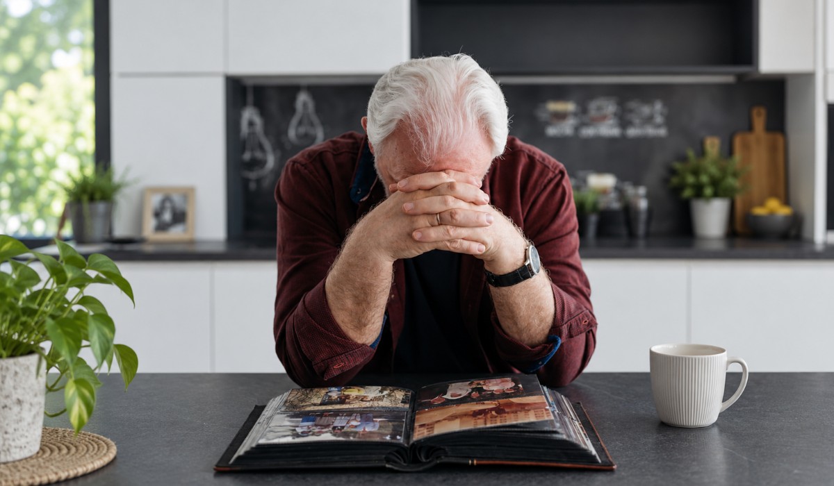 An older person struggling with dementia trying to remember people from his family photo book.